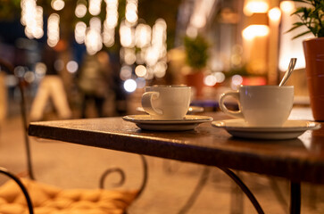 Coffee cup at outdoor wooden table during night life party
