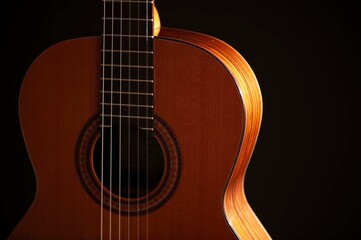 Obraz premium Classical Spanish flamenco guitar close up, dramatically lit isolated on black background with copy space.