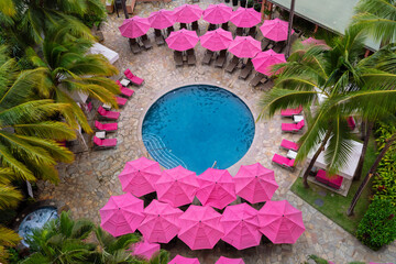 pink pool umbreallas around palm trees