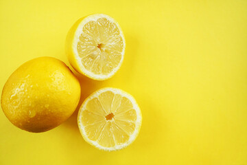 Whole and cut lemons on a yellow background