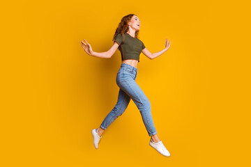 Fototapeta na wymiar Photo of positive charming cute girl dressed stylish clothes running looking empty space offer isolated on yellowa color background