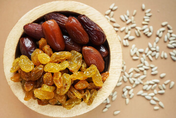 Dried dates and raisins in a wooden plate on a light background