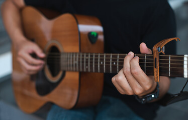 Close-up male hands holding guitar chords and playing acoustic guitar.