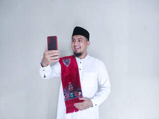 Moslem Asian man smiling happy when looking to his mobile phone