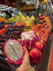 Marché de fruits et légumes à Barcelonne et un fruit du dragon dans une main