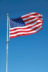 American flag flying against blue sky.