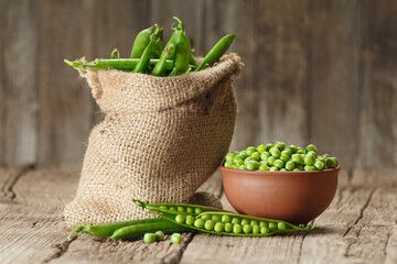 Green peas in closed and open pods, peeled peas in a bowl, organic green peas in burlap on a wooden background.