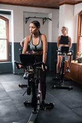 Fototapeta na wymiar two women are riding exercise bikes in a gym