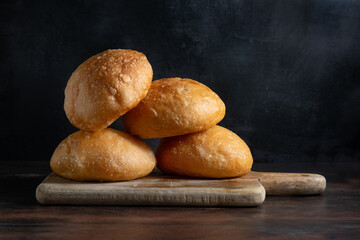 Baked buns. Freshly baked bread rolls on a cutting board. Black background