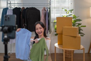 Young Asian Female online seller is using smartphone live on internet introduce new fashion cloth...