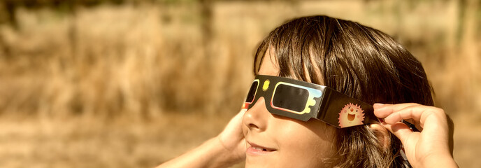 A young girl looking at the sun during a solar eclipse on a country park, family outdoor activity - 764169402