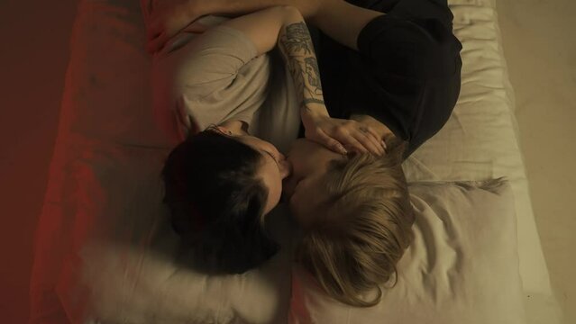 Top view young loving couple romantic time in bedroom. Man and woman half naked sensual lovers laying in bed together, passion, intimacy kissing, foreplay and bonding.