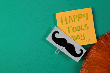 Happy Fools Day with mustache and greeting card on green background