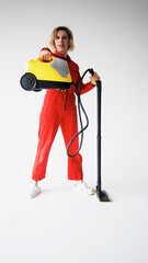 A young woman in a red jumpsuit is an employee of a cleaning company with a vacuum cleaner in her hands, highlighted on a white background