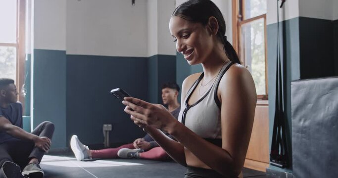 Athletic woman laughing at mobile device while working out in gym studio