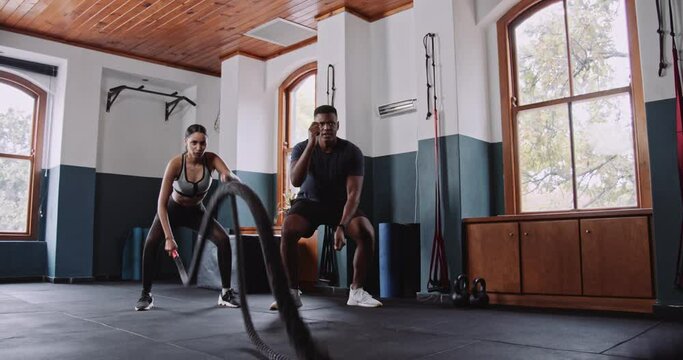 A man and woman workout with ropes in gym building