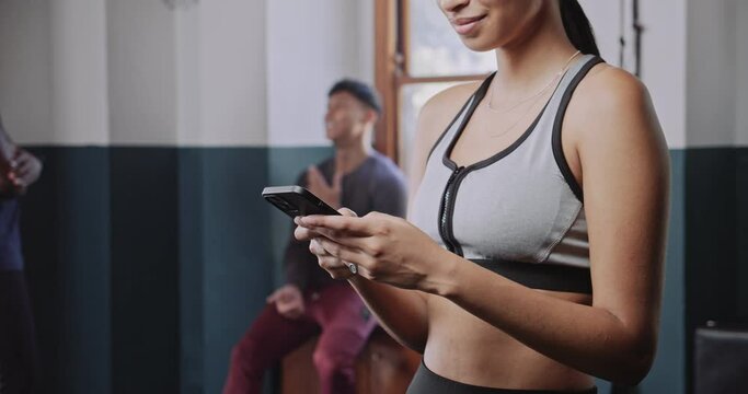 Multi ethnic woman smiling at her mobile device in gym studio.