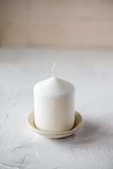 a candle in a ceramic candlestick on a beige background.