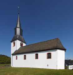 St Remigius church with white bell tower and slated roof in the old village Dohm-Lammersdorf, Eifel region in Germany