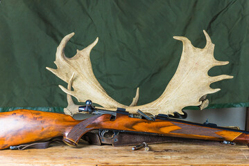 Beautiful hunting trophy deer antlers and hunting carbine on a wooden table