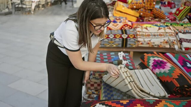 A woman browses colorful textiles at souq waqif, showcasing qatar's traditional marketplace culture.