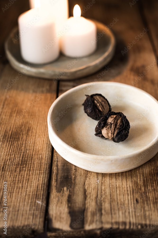 Wall mural walnuts on a ceramic dish on a wooden table against a background of lighted candles