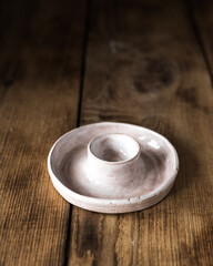 an empty round ceramic candlestick on a wooden table. Dark background.