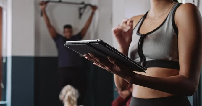 Medium shot of female fitness trainer using tablet in fitness studio 