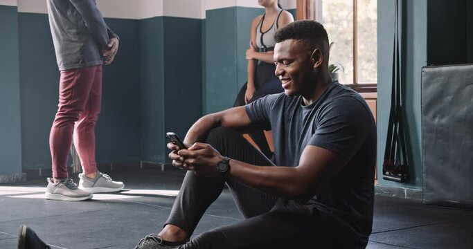 African American athlete smiles at cellphone while in a fitness studio 