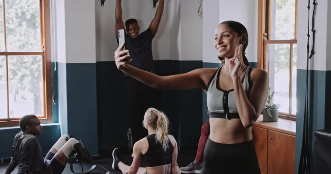 Multiethnic woman takes selfie in fitness studio after training 