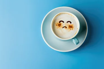 Foto op Plexiglas Cup of cappuccino with a sad face design in cinnamon, conveying a creative yet melancholic mood on a blue background - AI generated © qntn