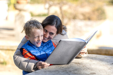 Boy with his mother with a loving expression, reading a book in a rest area