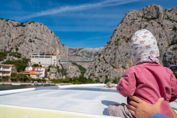 Toddler on boat on Cetina river merging with Adriatic Sea in coastal town Omis, Split-Dalmatia,...