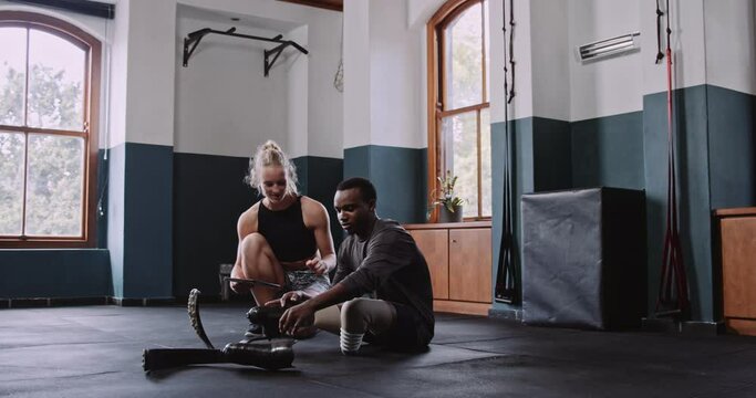 Caucasian female trainer uses tablet to show disabled athlete a training plan 