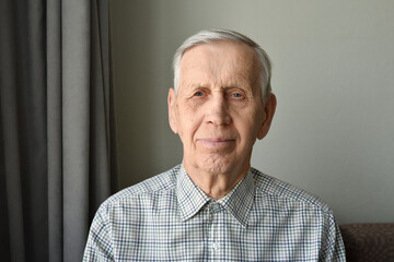 Portrait of an old man, content and happy, 85 years of age. The elderly man is wearing a shirt and is looking into the camera with a smile on his face.