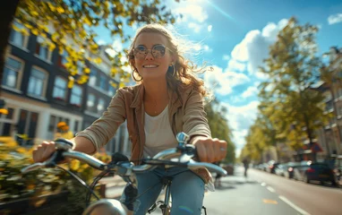 Poster A woman is riding a bicycle down a street with a smile on her face © natalia