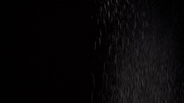 White flour falling from the top against black background