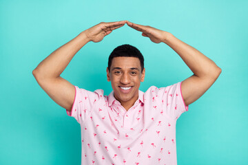 Photo of cheerful friendly guy toothy smile arms demonstrate roof above head symbol isolated on...