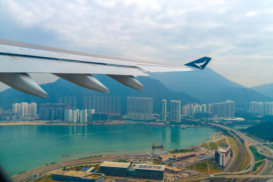 iew of the wings of a Cathay Pacific airplane through the window of the plane, flying over Hong Kong