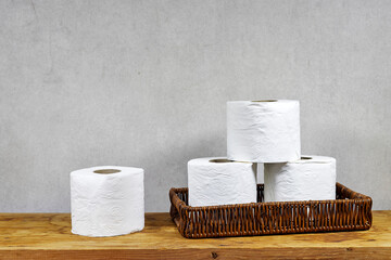 whicker basket with rolls of toilet paper on  wooden board table with copy space