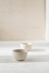 two small white ceramic saucepan on a beige background with a place for text. Japanese style. A cup for sake/tea/sauce pan.