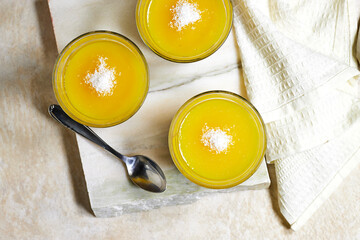 Homemade layered vegan dessert of baked coconut cream and chocolate and orange fruit jelly on marble stone