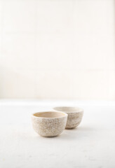 two ceramic tea bowls. Ceramic saucepan for handmade sauce. Minimalism style. Front view. Japanese ceramics. Tea ceremony. Close-up.