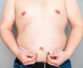 Man Holding Measuring Tape Around Overweight Belly