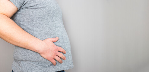 Side view of overweight man's belly with hand resting