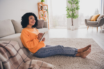 Fototapeta premium Photo portrait of lovely young lady thinking sit floor write notes dressed casual orange clothes cozy day light home interior living room