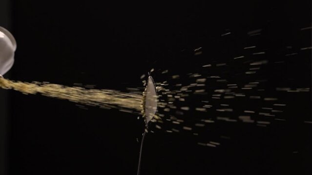 Slow motion of pouring sugar in spoon in dark studio