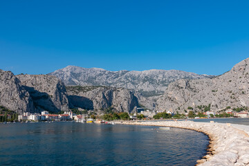 Naklejka premium Scenic hiking trail Omiski lukobran in coastal town Omis, Split-Dalmatia, South Croatia, Europe. Majestic rugged coastline of Omis Riviera surrounded by steep Dinara mountains. Balkans in summer