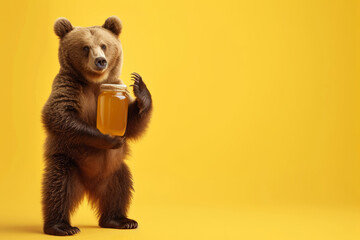 A bear on two legs holding a jar of honey isolated on a yellow background with space for text or...