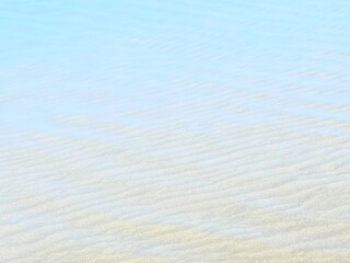 Ligh blue ocean water white sand ripples background.